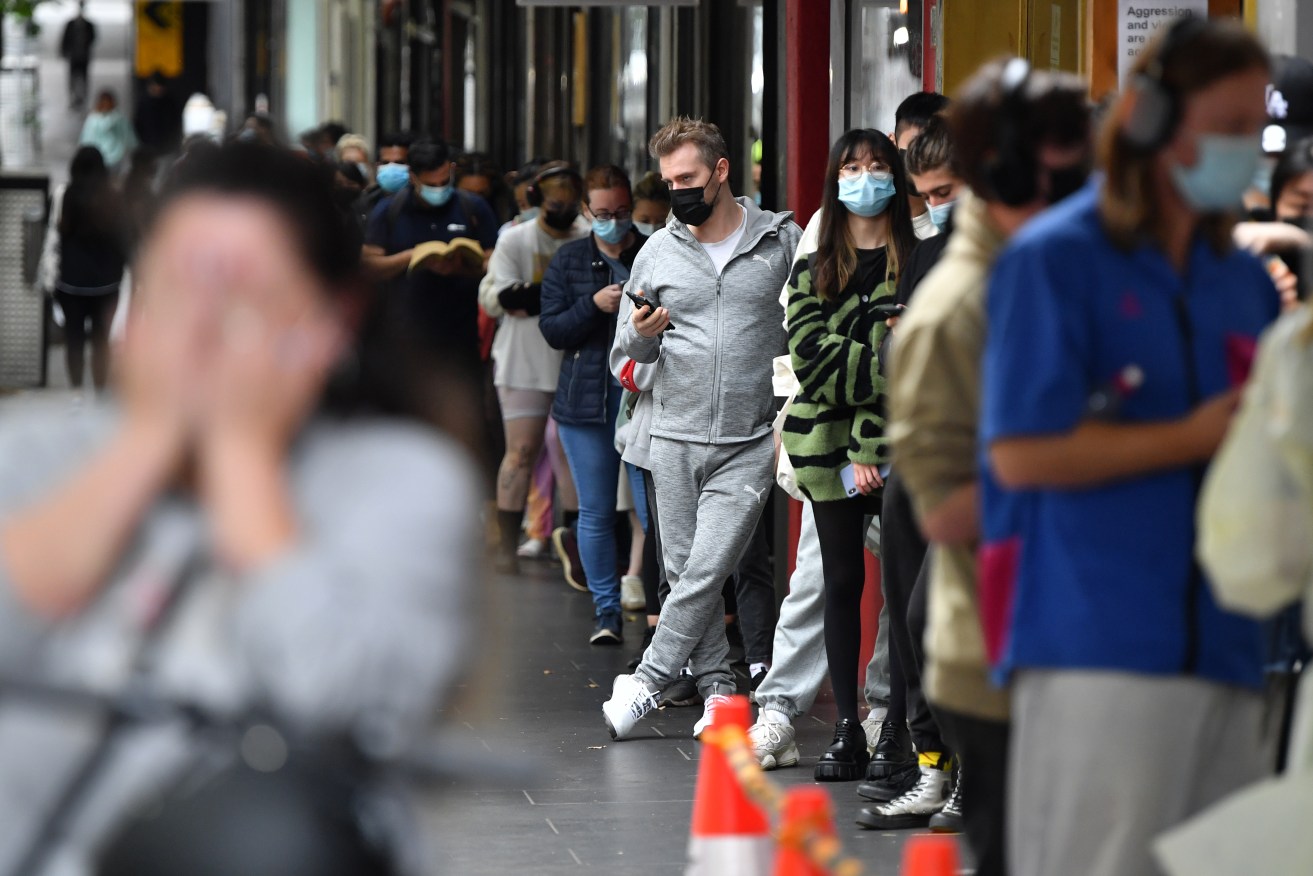 People queue at a walk-in COVID-19 testing site at in Melbourne, Wednesday, January 5, 2022. COVID-19 testing pressures in Victoria have prompted four private pathology labs to close 54 sites while they catch up on a backlog of results. (AAP Image/Joel Carrett) NO ARCHIVING