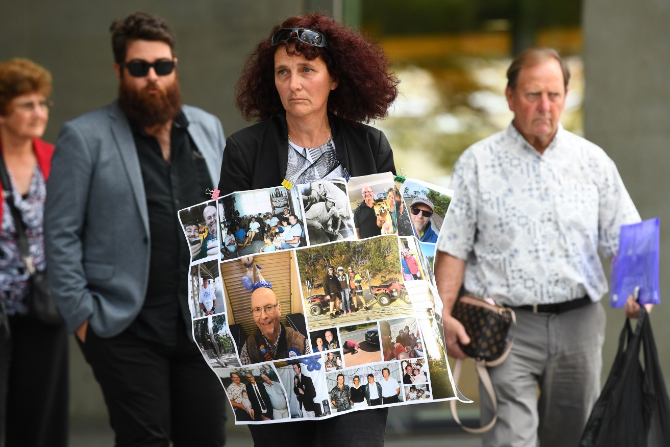 Paula Seibel (centre) leaves the Brisbane District court holding family photos as a tribute to her husband, Ian Seibel, who was killed after an unlicensed driver sped through a red light and hit the couple. (AAP Image/Jono Searle) 
