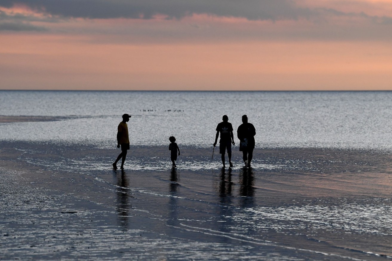 Locals walk in shallow waters at sunset, looking for native Shellfish in Weipa, in far North Queensland, Sunday, July 17, 2022. (AAP Image/Jono Searle) NO ARCHIVING