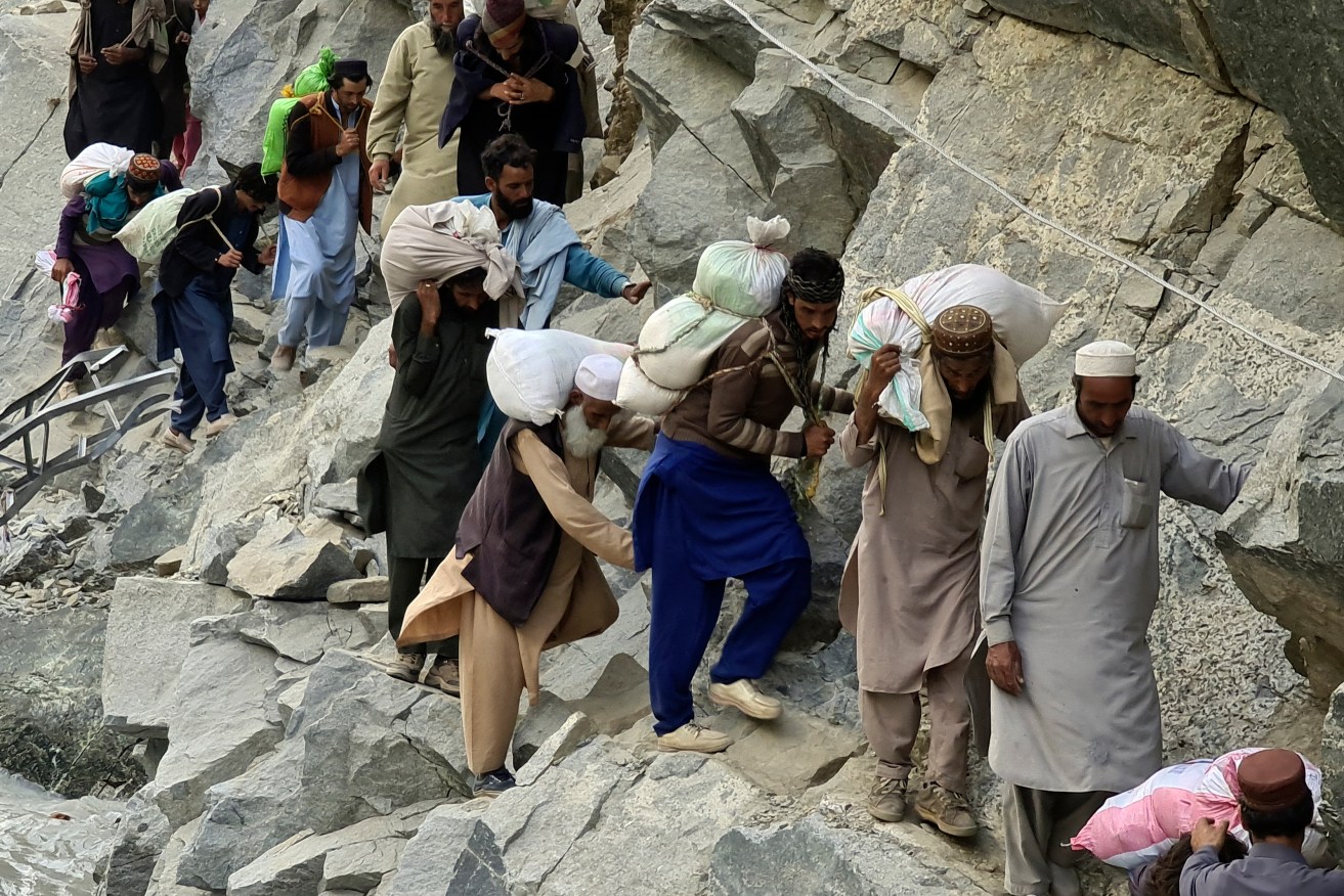 Local residents cross a portion of road destroyed by floodwaters in Kalam Valley in northern Pakistan. Officials warned Sunday that more flooding was expected as Lake Manchar in southern Pakistan swelled from monsoon rains that began in mid-June and have killed nearly 1,300 people. (AP Photo/Sherin Zada)