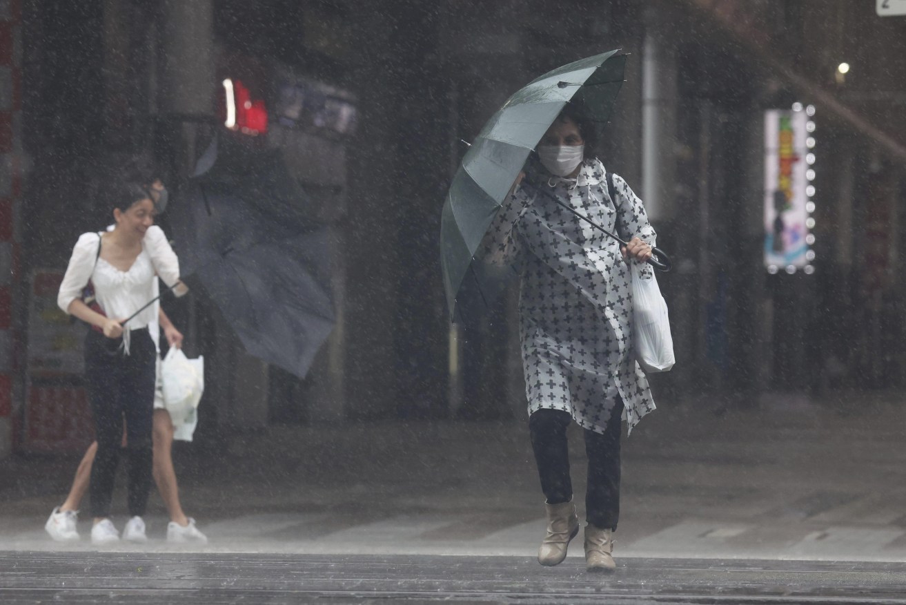 People walk at a street in a storm in Kagoshima Prefecture on Sept. 18, 2022.  According to Japan Meteorological Agency, Typhoon Nanmadol has become the highest classification of "violent" and it issued a special warning for southwestern regions in Kyushu, where a large-scale disaster could be imminent. The massive typhoon will keep on hitting Japan through early next week. ( The Yomiuri Shimbun via AP Images )