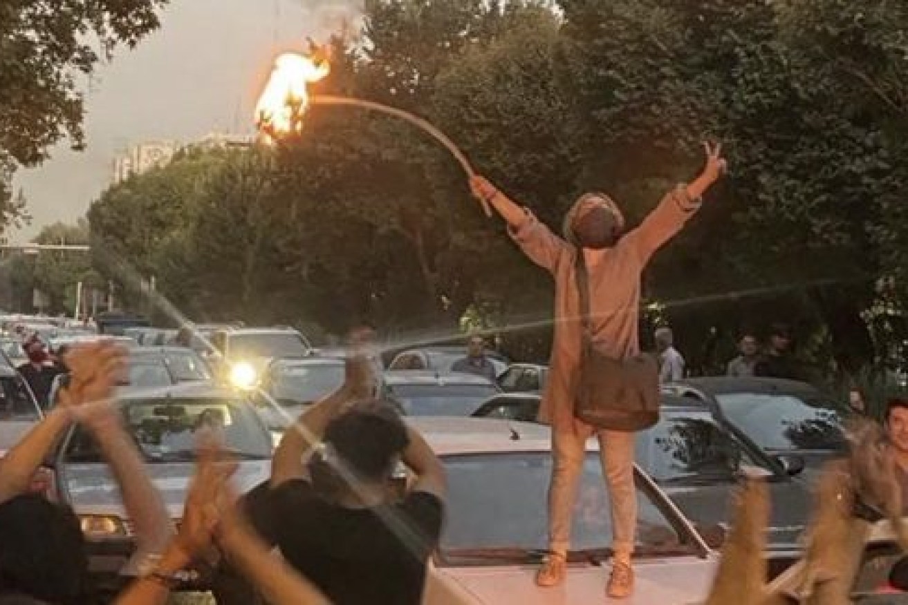 A woman burns her headscarf during a demonstration in Iran. (Image: Twitter)