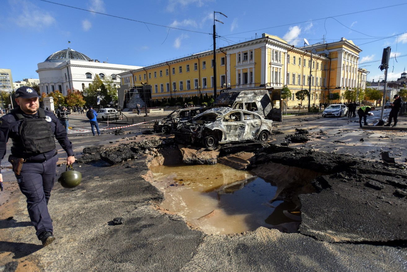 A police officer (L) walks past destroyed cars at a damaged road after shelling in downtown Kyiv overnight. Explosions have been reported in several districts of the Ukrainian capital Kyiv, with rescuers extinguishing fires and helping the victims among the civilian population  EPA/OLEG PETRASYUK