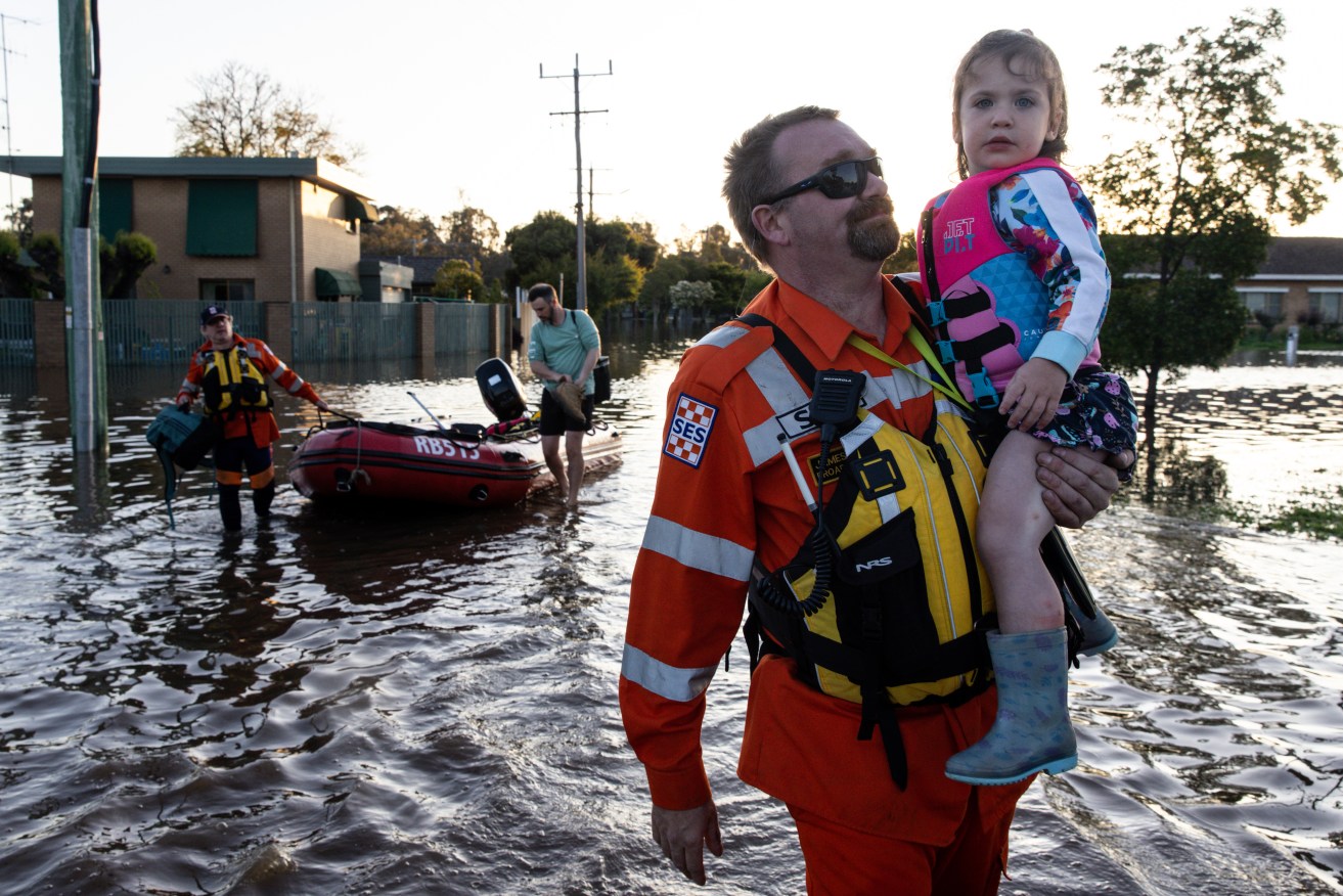 SES personnel help a family leaving their home in Shepparton, Victoria. The flooding crisis has worsened in Victoria's north with residents told to move to higher ground. (AAP Image/Diego Fedele) 