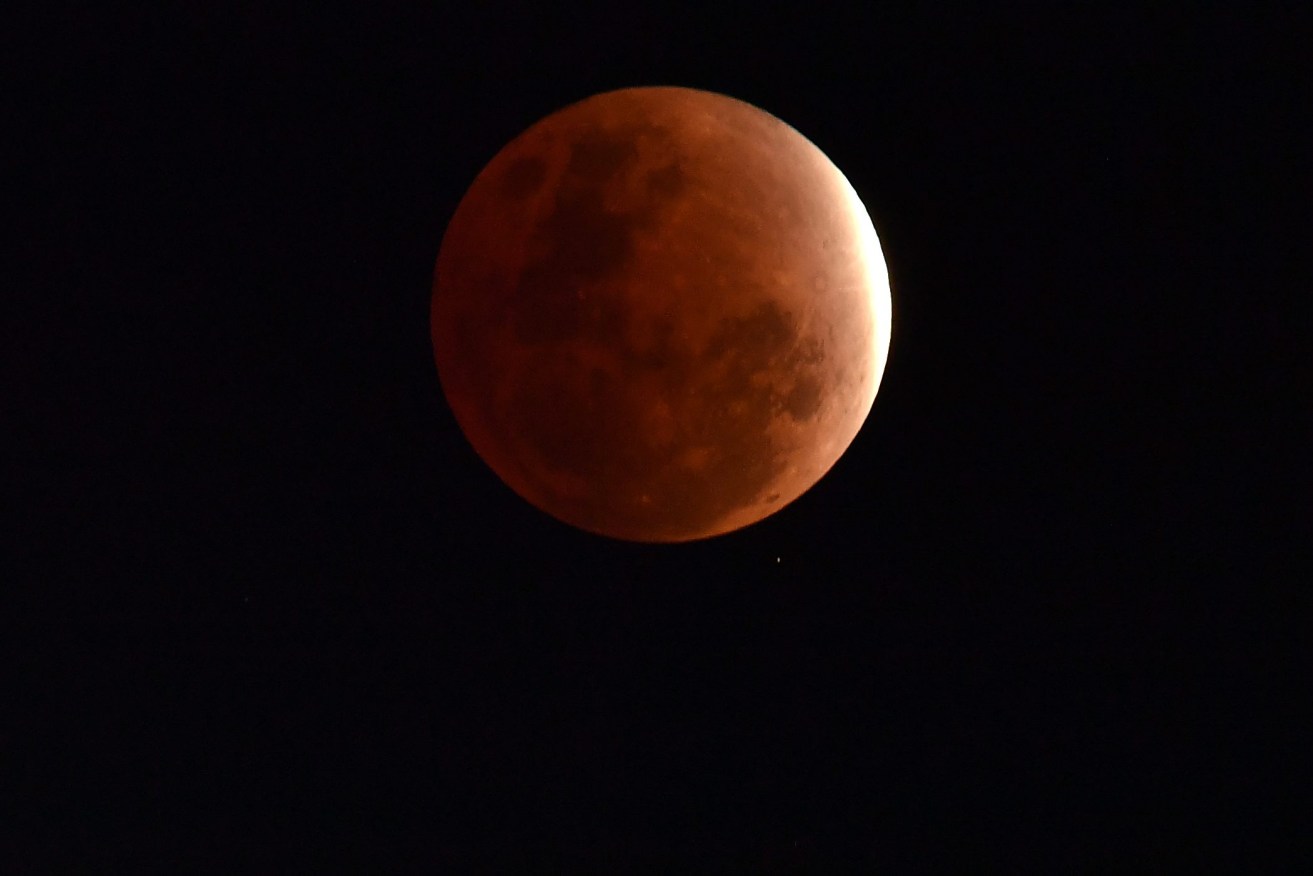 The Moon is seen as the earth's shadow covers the moon during a partial lunar eclipse over Brisbane.  Friday, Nov. 19, 2021. The moon will pass almost totally into the earth's shadow during the partial lunar eclipse, sometimes referred to as a 'blood moon' due to the reddish tinge. (AAP Image/Darren England) 