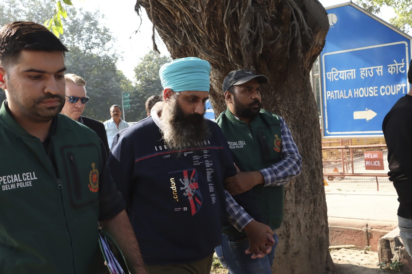 Policemen escort Rajwinder Singh, 38, after he was arrested in New Delhi, India, Friday, Nov. 25, 2022. The Indian nurse accused of killing Toyah Cordingley, 24, an Australian woman in Queensland in 2018 was arrested by Delhi Police on Friday.  (AP Photo/Dinesh Joshi)