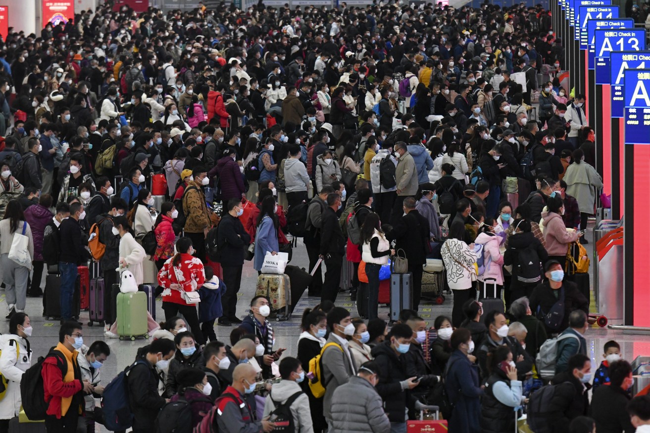 People wearing face masks with their luggage prepare to catch their trains at the North Railway Station in Shenzhen in south China's Guangdong province, Saturday (Liang Xu/Xinhua via AP)