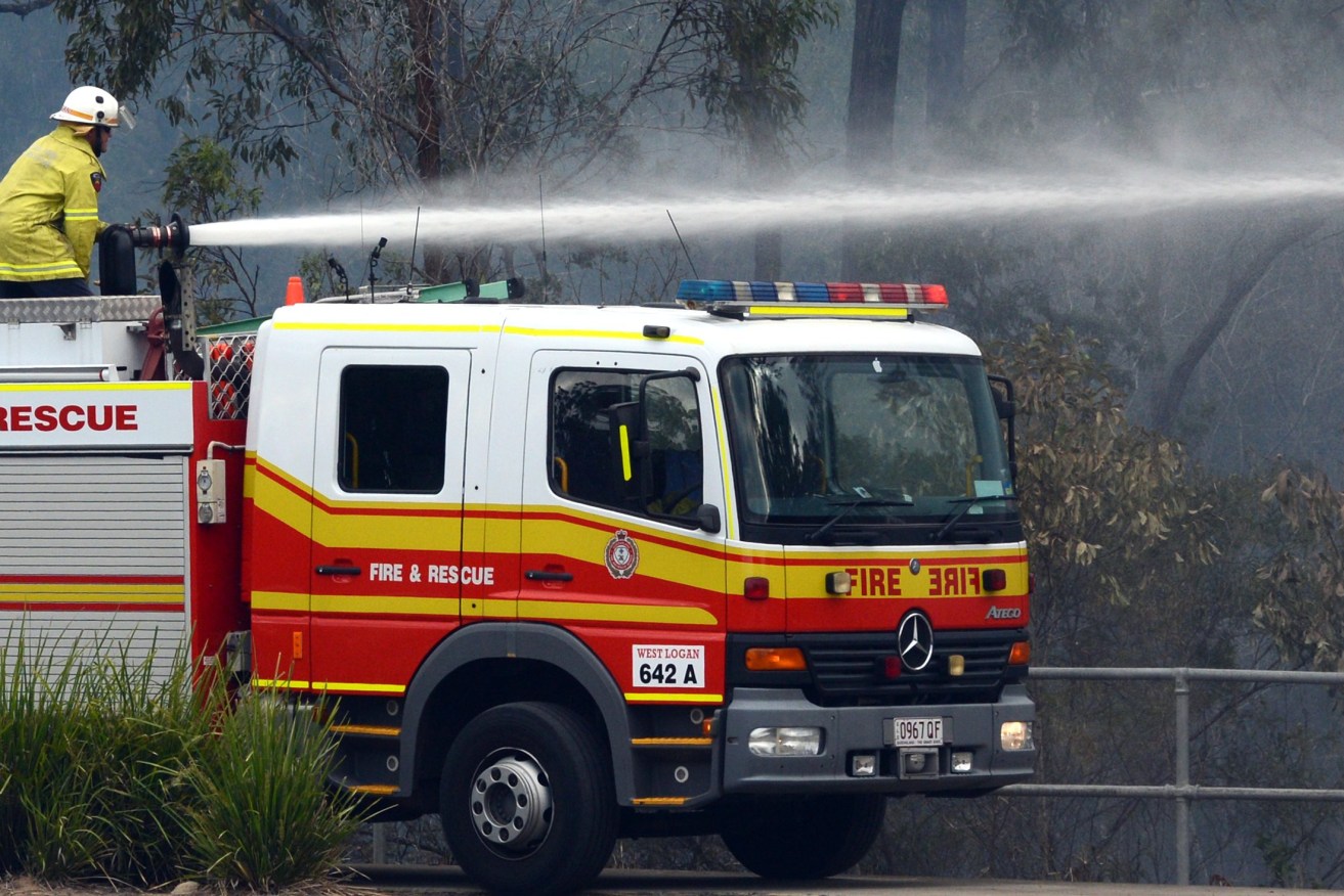 A Queensland Fire and Rescue (QFRS) crew extinguishes a grass fire.  (AAP Image/Dan Peled) 