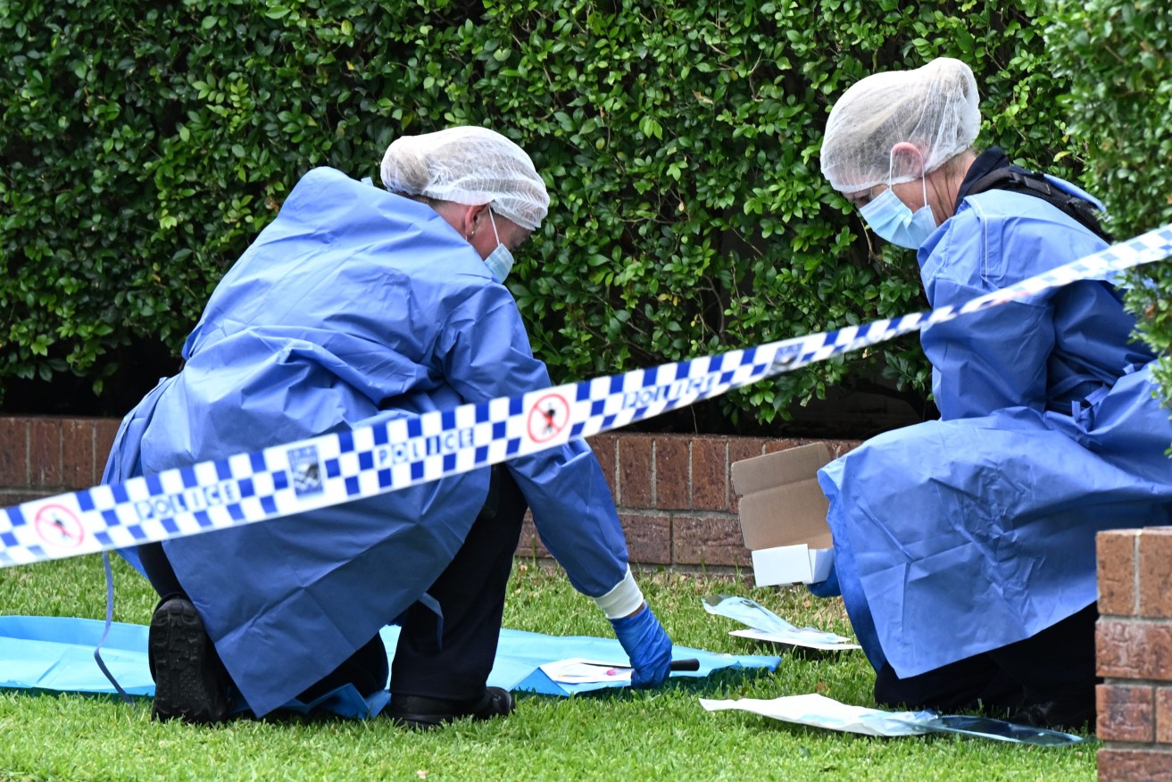 Forensic police are seen with a knife at the scene of a small fire and wounding at the Grange in Brisbane. (AAP Image/Darren England) 