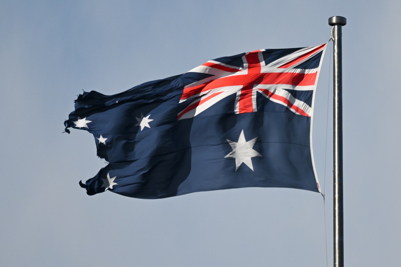 A tattered Australian flag is seen on top of the Australian Parliament House in Canberra, Wednesday, March 8, 2023. (AAP Image/Lukas Coch) NO ARCHIVING