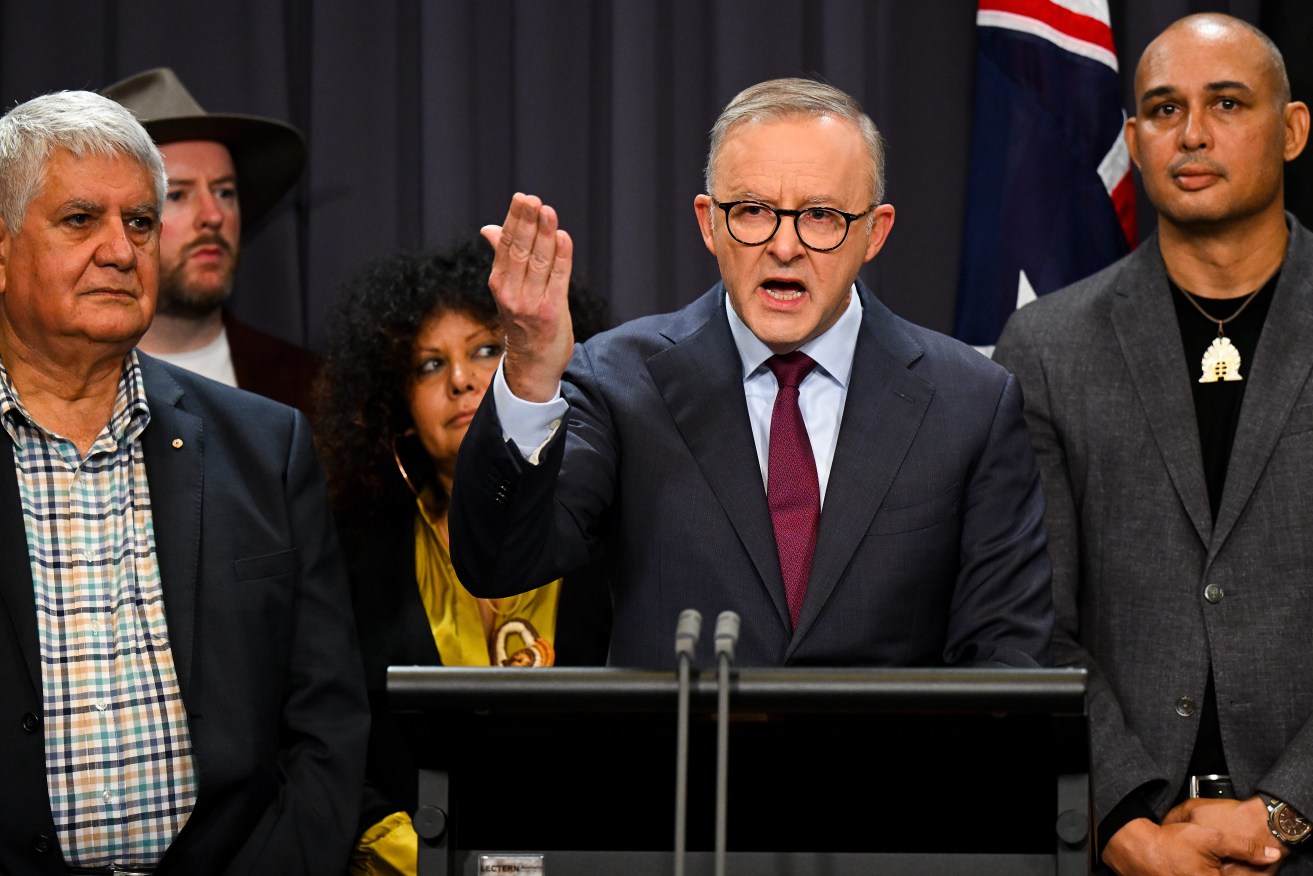 Australian Prime Minister Anthony Albanese surrounded by members of the First Nations Referendum Working Group, including former Liberal Party minister Ken Wyatt, left,  speaks to the media during a press conference at Parliament House in Canberra (AAP Image/Lukas Coch) 