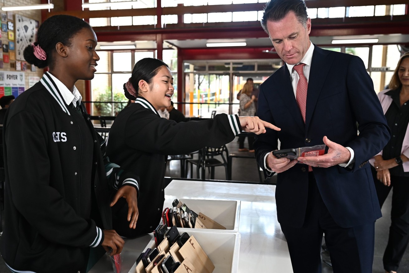 New South Wales Premier Chris Minns learns how to check a phone in during a visit to Condell Park High School. All parents affected will be offered tutoring - over the phone. (AAP Image/Steven Saphore) 