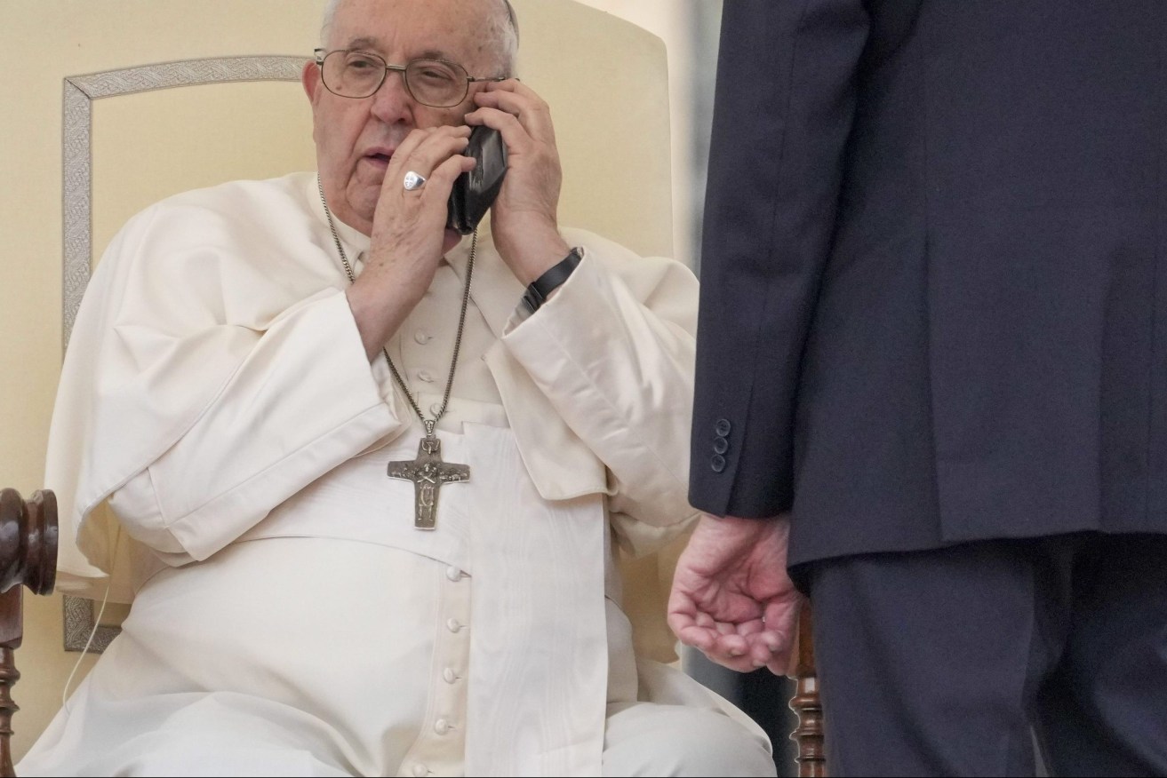 Pope Francis talks on the phone during his weekly general audience in the St. Peter's Square at the Vatican, Wednesday, May 17, 2023. (AP Photo/Andrew Medichini)