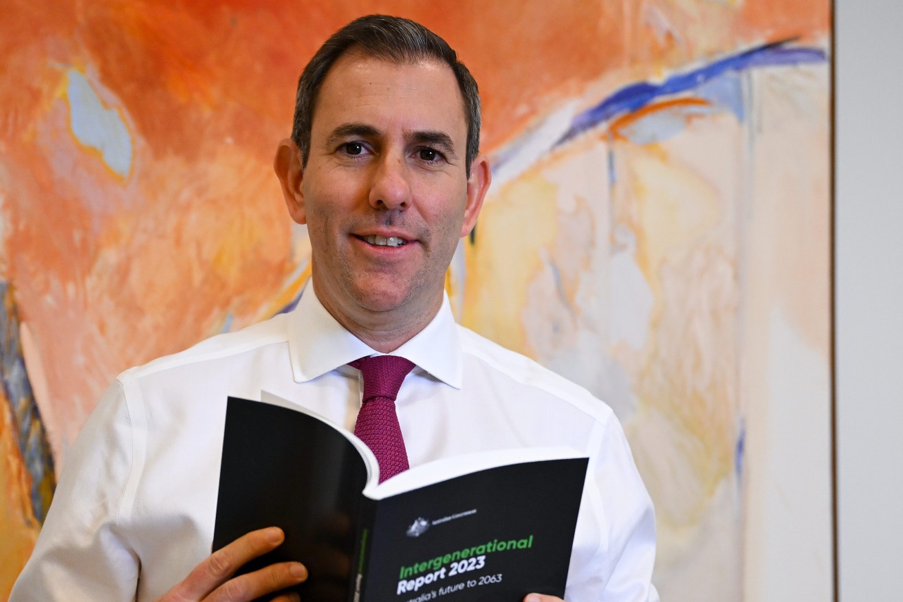 Australian Treasurer Jim Chalmers poses for photographs holding a copy of the Intergenerational Report 2023 at Parliament House in Canberra, Thursday, August 24, 2023. (AAP Image/Lukas Coch) 