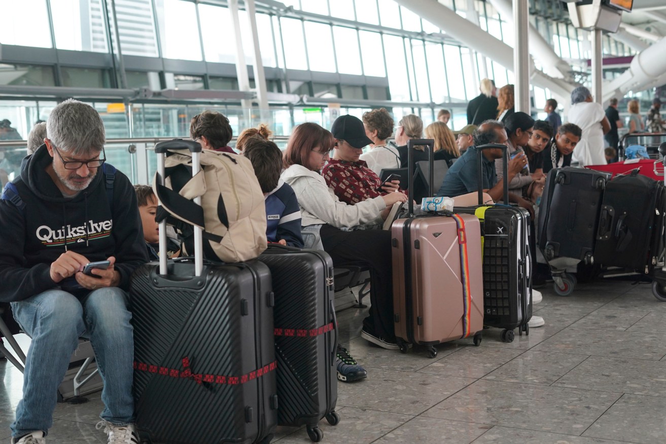 Passengers are seen waiting for delayed flights in London's Heathrow airport. The British government says a cyberattack was not the cause of a breakdown at the nationwide air traffic control system that saw hundreds of flights delayed and canceled. The problem hit on a late-summer holiday Monday that is one of the busiest days of the year for air travel.  (Lucy North/PA via AP)