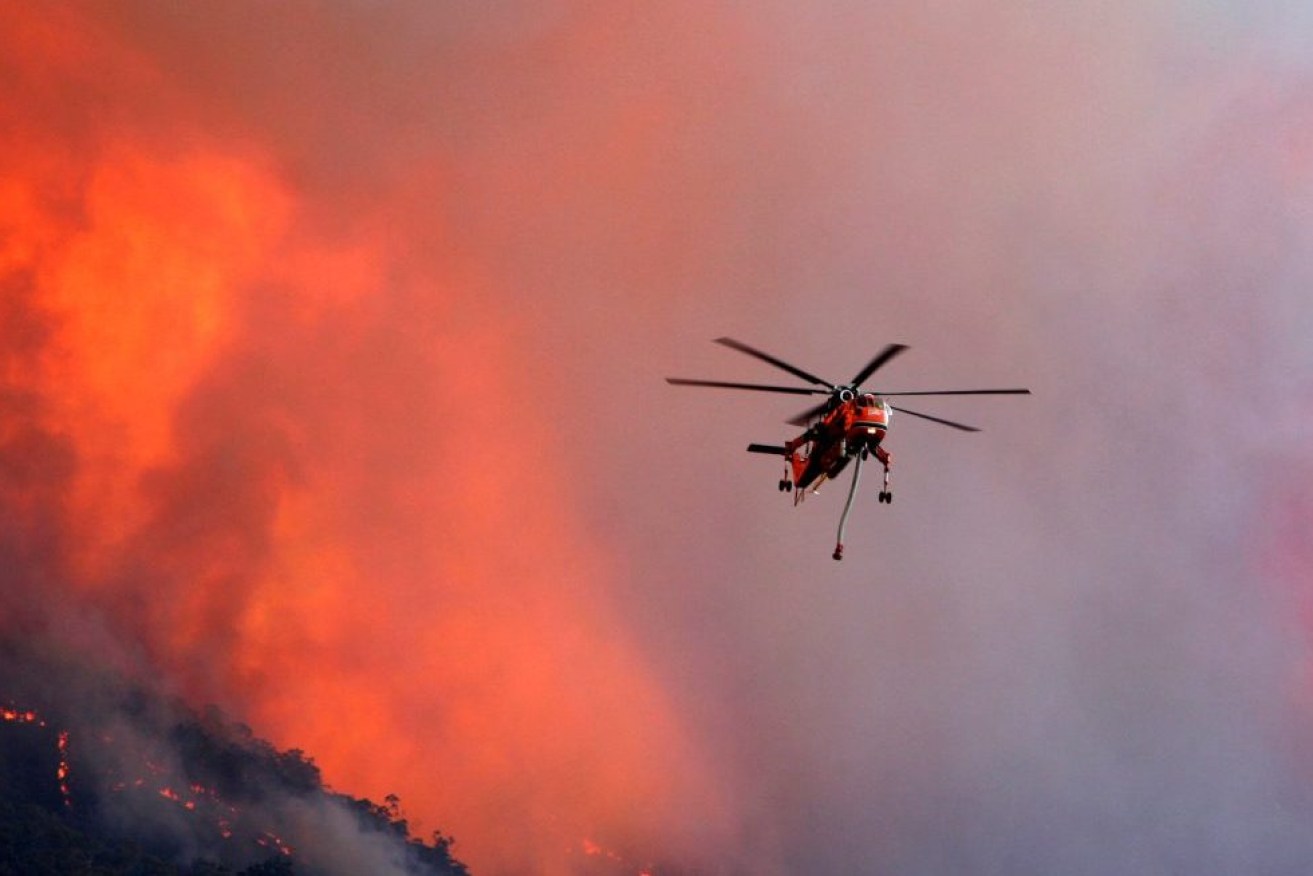 A firefighter helicopter battles a blaze at Tawonga Gap in Victoria, (AAP Image/Chris Hocking) NO ARCHIVING