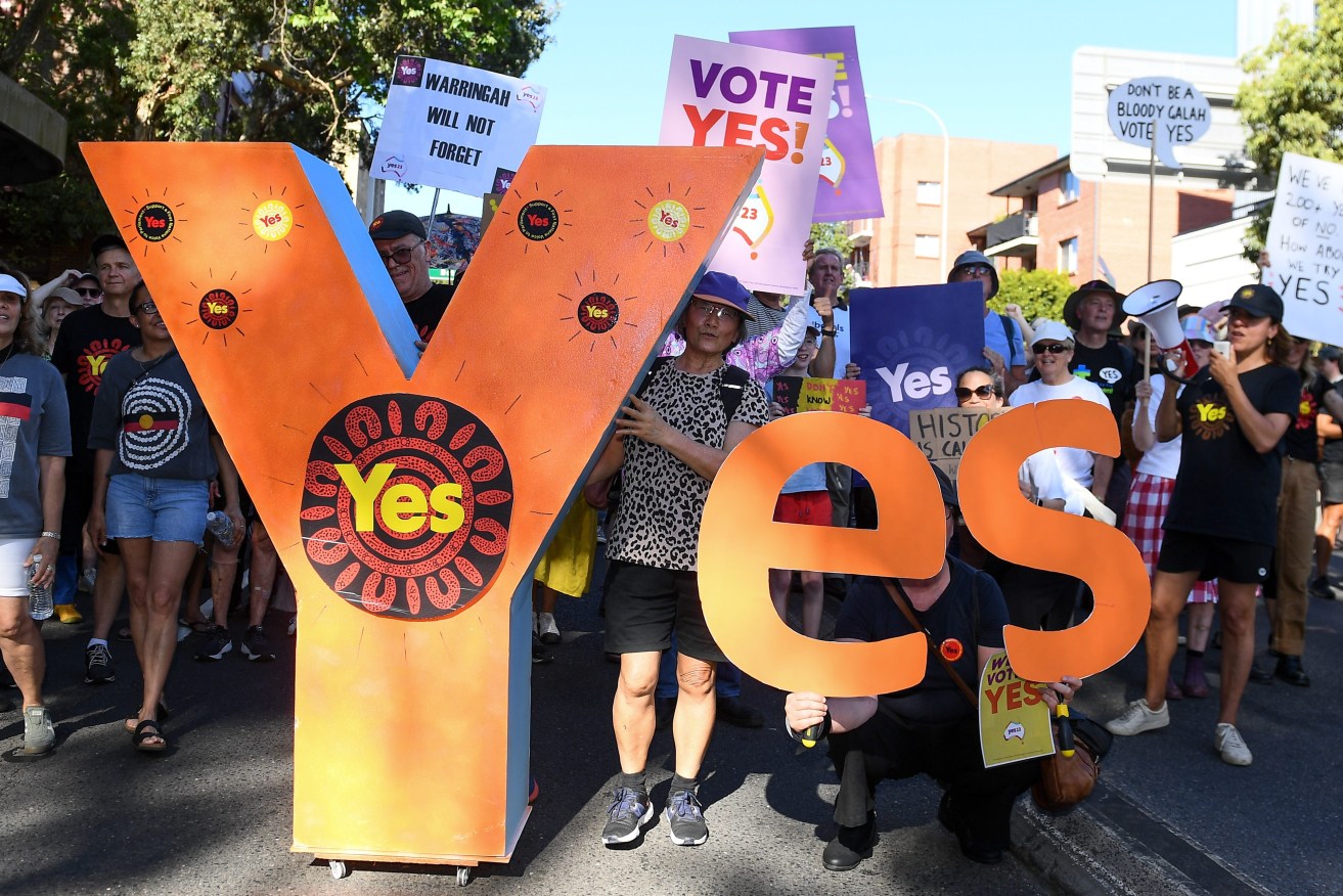 People hold up a Yes sign during a walk for the Yes vote event in Sydney. (AAP Image/Steve Markham)