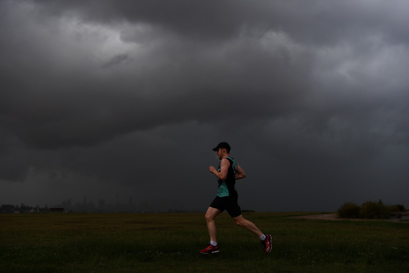 A jogger is seen at Dudley Page Reserve as a large storm moves over the CBD in Sydney, Monday, January 4, 2021. A severe thunderstorm warning has been issued for parts of the Blue Mountains, Hawkesbury and Sydney areas, with large hailstones, damaging winds and heavy rain expected. (AAP Image/Dean Lewins) NO ARCHIVING