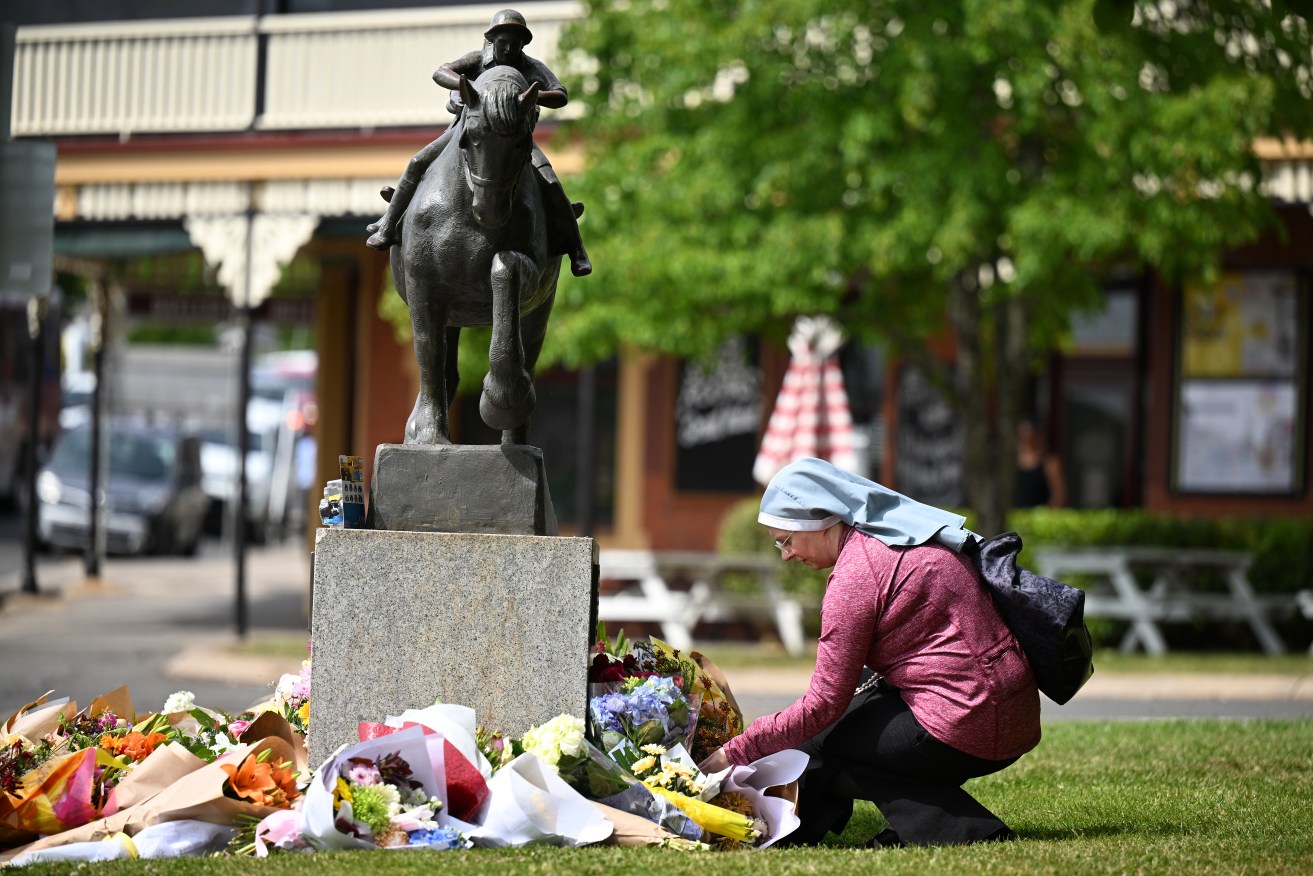 A mourner observes the tributes and flowers left outside of the Royal Daylesford Hotel in Daylesford, Victoria, Monday, November 6, 2023. Five people, including two children, have died and there are multiple others injured after an SUV car crashed into a pub in regional Victoria. (AAP Image/James Ross) NO ARCHIVING