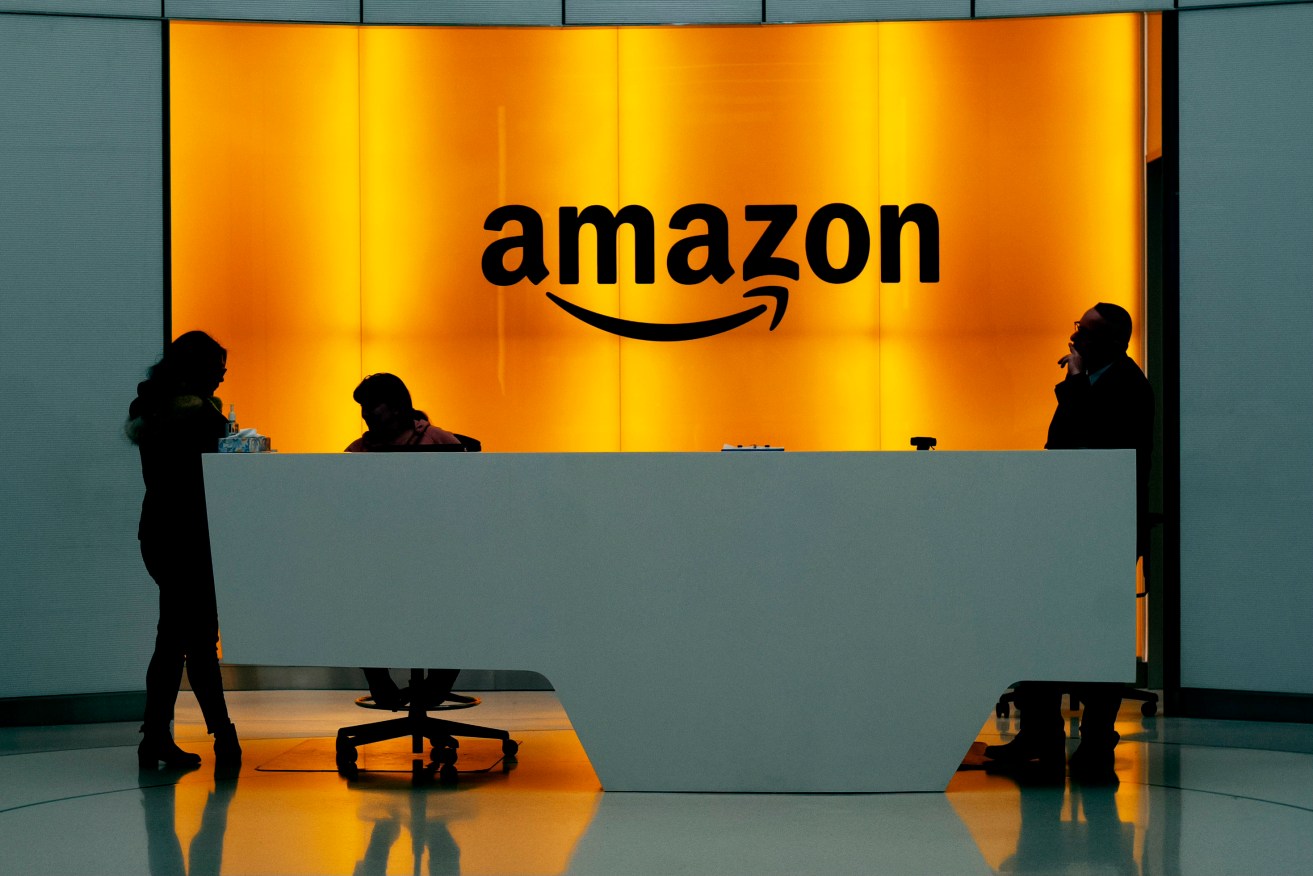 FILE - In this Feb. 14, 2019 file photo, people stand in the lobby for Amazon offices in New York. Amazon finally has its answer to ChatGPT.  The tech giant said Tuesday, Nov. 28, 2023, it will launch Q – a generative-AI powered chatbot for businesses.  (AP Photo/Mark Lennihan, File)