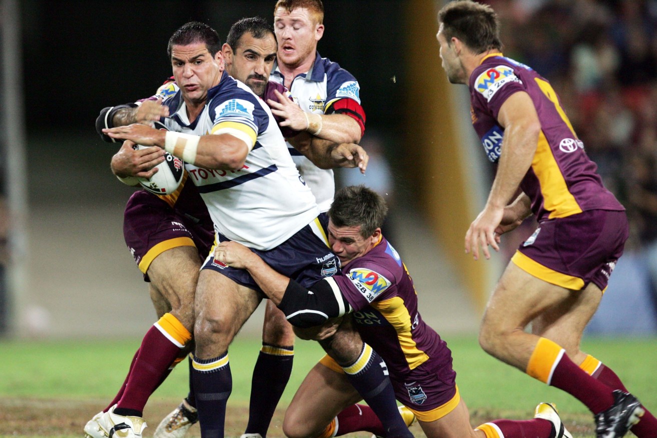 Carl Webb bursts through a tackle by the Broncos' Tonie Carroll and Shaun Berrigan in an NRL match in 2007. Webb has died aged 42. (AAP Image/Colin Whelan/Action Photographics) 