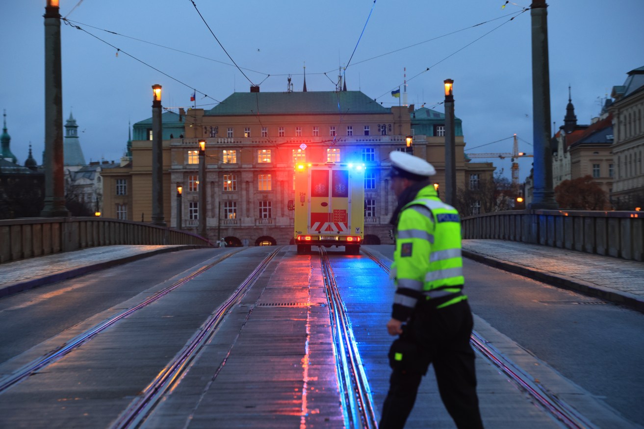 A Police officer stands guard as an ambulance rushes to the scene of a shooting in central Prague  EPA/MARTIN DIVISEK