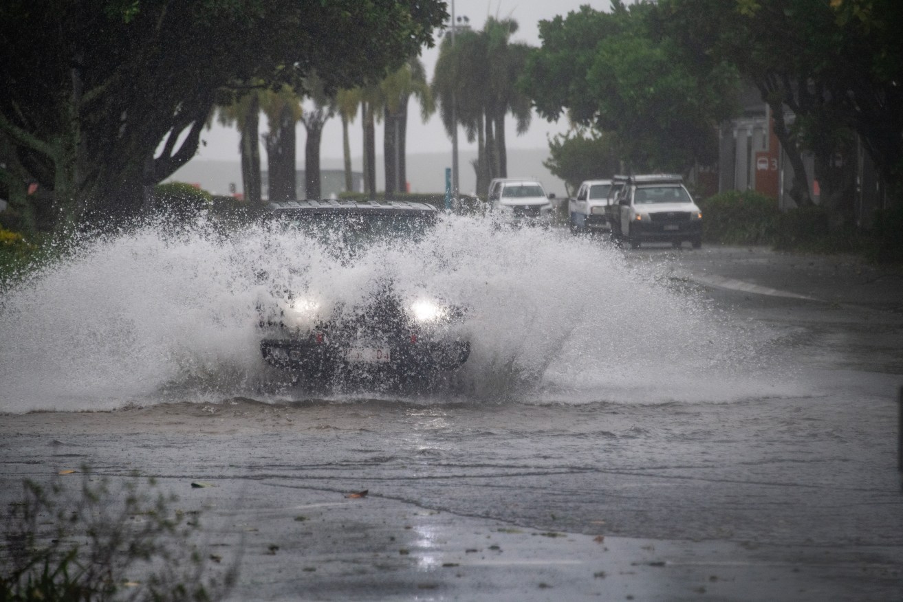 Cars drive through water at the Cairns Esplanade in Cairns, Thursday, December 14, 2023. People in Tropical Cyclone Jasper's destructive path have been warned they are still not safe despite the system weakening in far north Queensland. (AAP Image/Brian Cassey) 