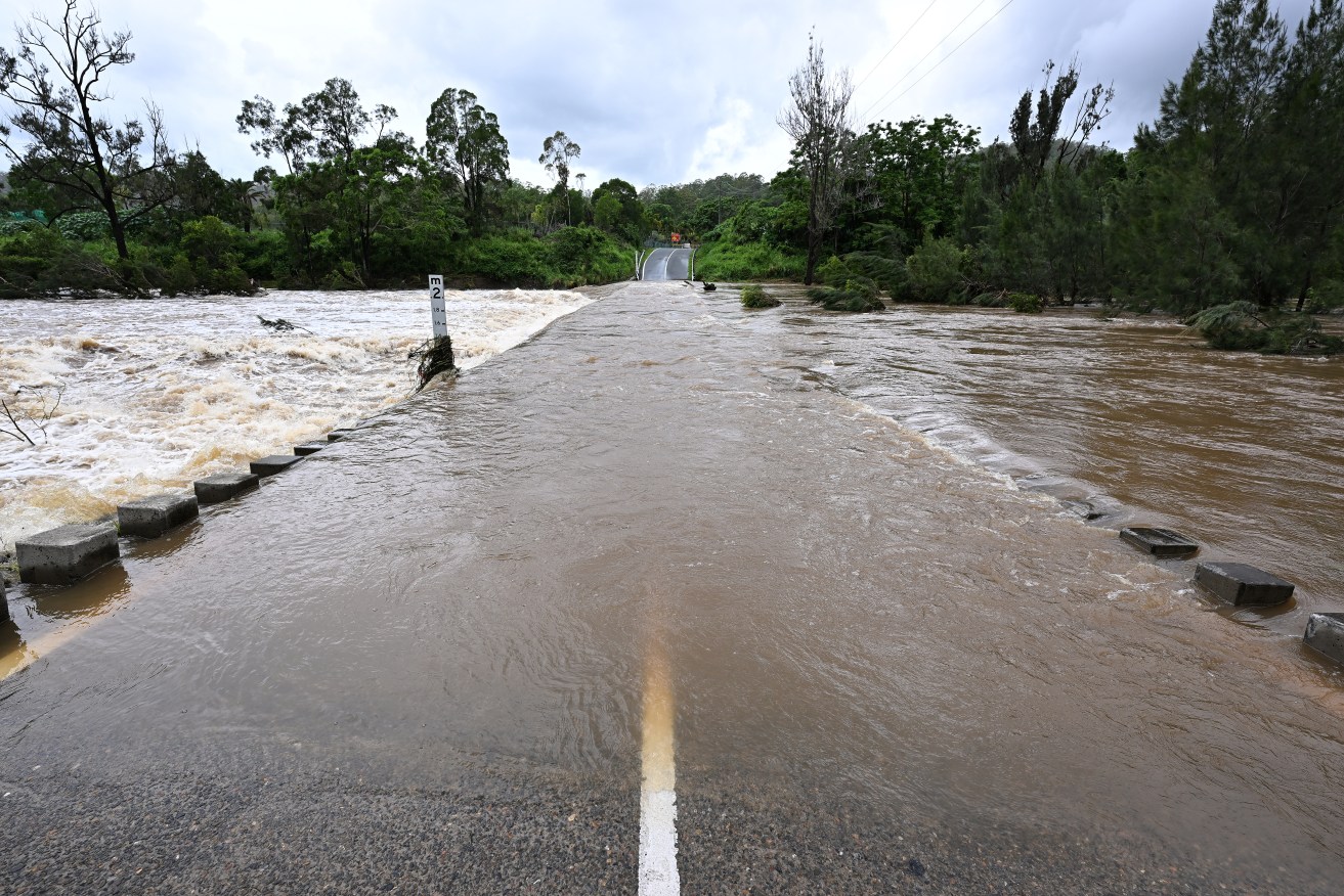 The Coomera river is seen cutting Clagiraba Road on the Gold Coast Tuesday, January 2, 2024. With rain easing, rivers and creeks throughout southeast Queensland and northern NSW remain with minor flooding following several days or torrential rainfall. (AAP Image/Dave Hunt) NO ARCHIVING