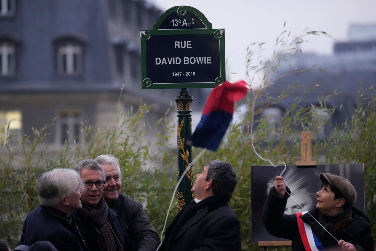 Officials unveil the street sign of singer David Bowie during a ceremony in Paris, Monday, Jan. 8, 2023. The city of Paris is immortalizing late British music icon David Bowie by naming a street after him in the city's southeast on what would have been his 77th birthday on Monday. (AP Photo/Christophe Ena)
