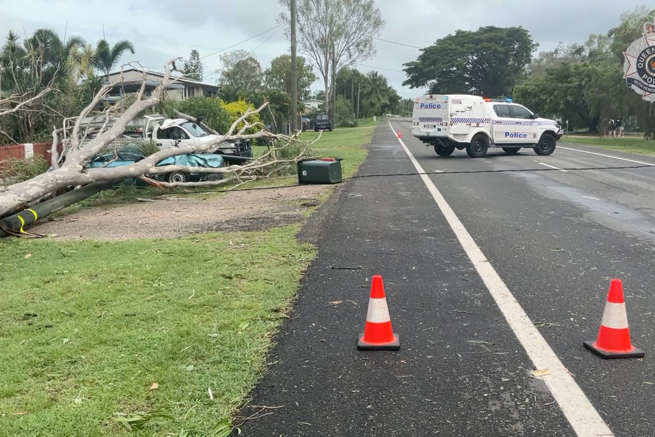 A supplied image obtained on Friday, January 26, 2024, of fallen power line and vehicles crushed by trees at Riverway Drive, Kelso, Townsville. Cyclone Kirrily has been downgraded to a tropical low after crossing the Queensland coast northwest of Townsville and leaving tens of thousands of properties without power. (AAP Image/Supplied by Queensland Police Service) 