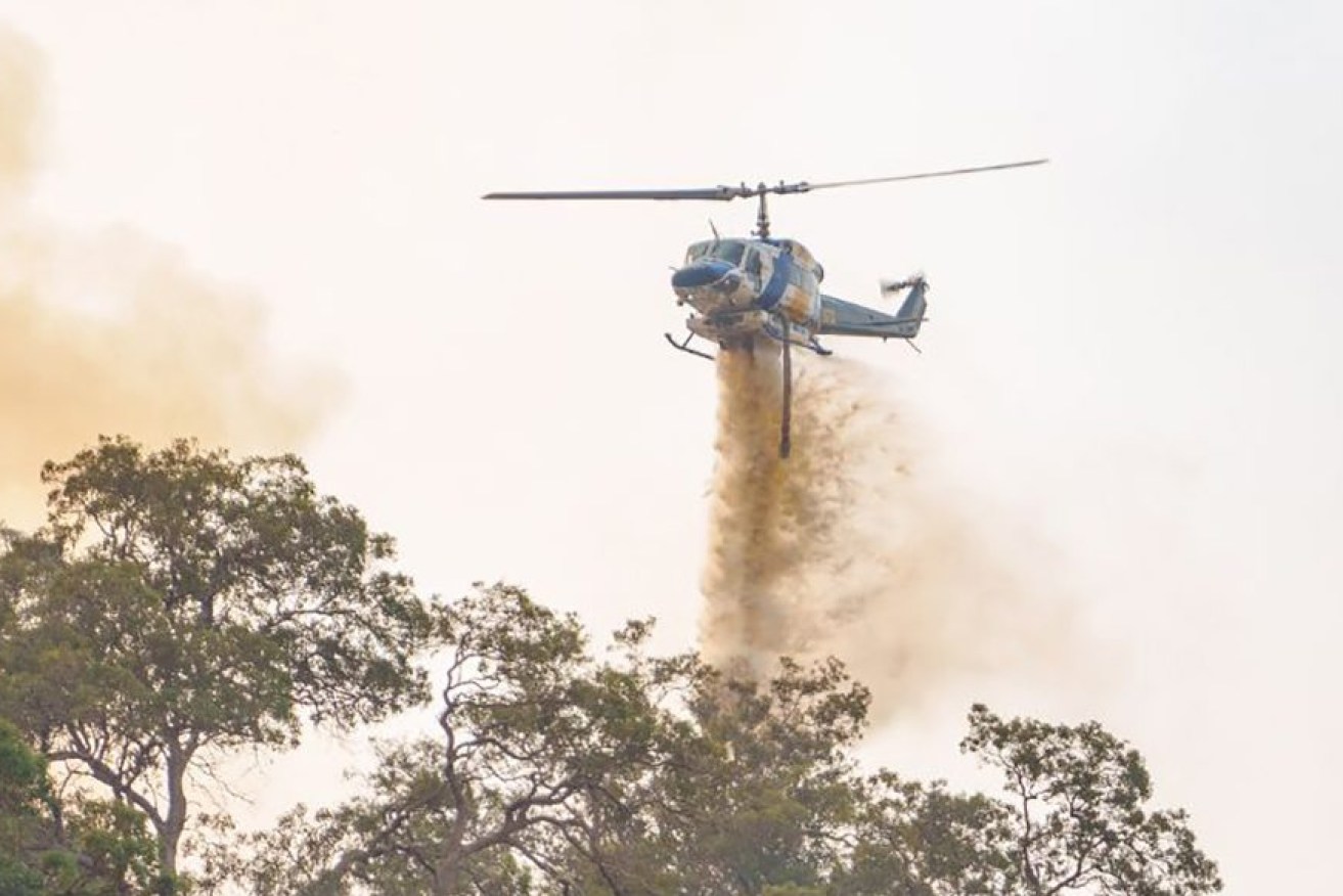 A supplied image obtained on Saturday, December 23, 2023, shows a helicopter near a bushfire in Keysbrook, Perth. Multiple blazes across Western Australia are testing firefighters, with authorities warning there are more "difficult" days ahead.(AAP Image/Supplied by Department of Fire and Emergency Services WA)