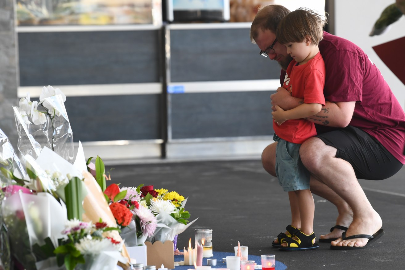 Residents lay flowers near a crime scene in Ipswich, West of Brisbane Monday following the murder of an elderly woman at a shopping centre car park near Brisbane. (AAP Image/Jono Searle) 