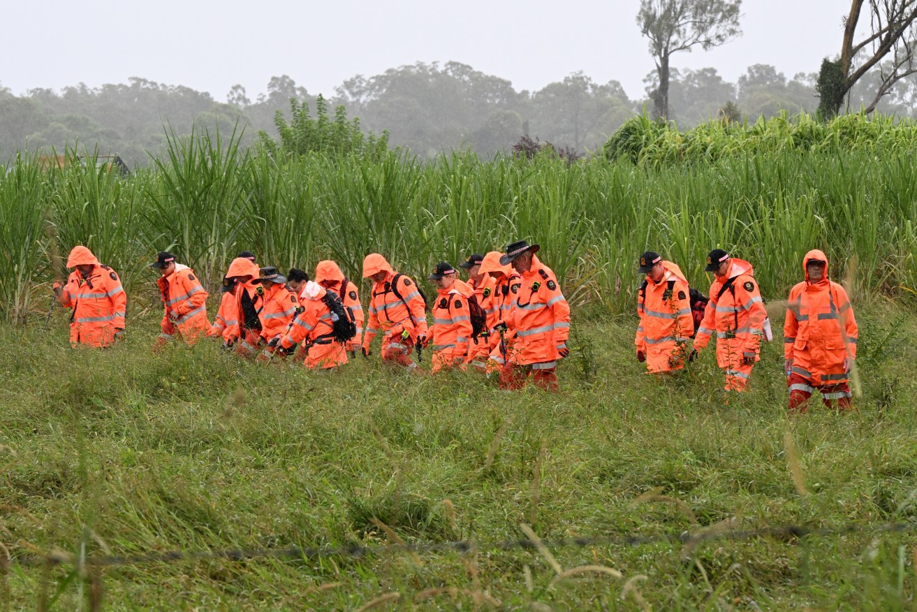 Queensland State Emergency Service (SES) volunteers are seen searching a property at the scene of a death in Woodhill,. A man has been charged with murder amid allegations a woman was fatally injured after being run over by a tractor in Queensland. (AAP Image/Darren England) 