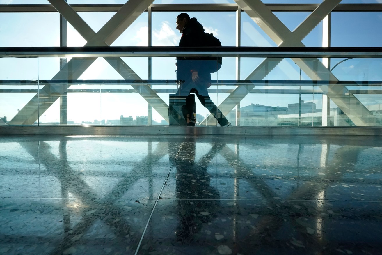 FILE - A traveler walks along a moving walkway between terminals at Logan International Airport in Boston, the day before Thanksgiving, Wednesday, Nov. 23, 2022. Logan is one of the three biggest airports in New England slated to make improvements to control towers, gates and mechanical systems under a nearly $1 billion federal plan to strengthen the nation's air travel infrastructure. (AP Photo/Steven Senne, File)