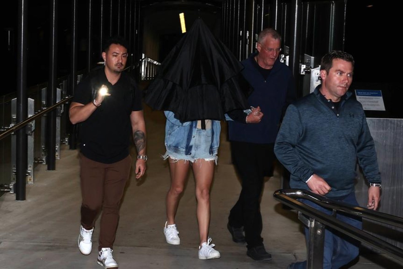 Taylor Swift (covered with umbrella) holds her dad’s hand (second from right) at Neutral Bay wharf on Tuesday morning. Picture: Matrix