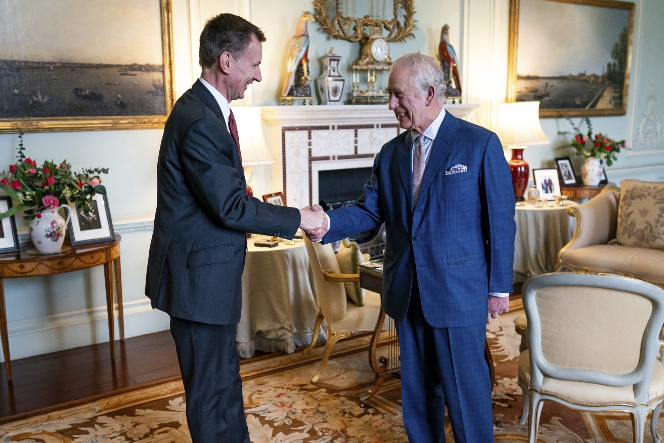 King Charles III, right, shakes hands with the Chancellor of the Exchequer, Jeremy Hunt, left, in the private audience room at Buckingham Palace, London, England, Tuesday, March 5, 2024. (Aaron Chown/PA via AP)