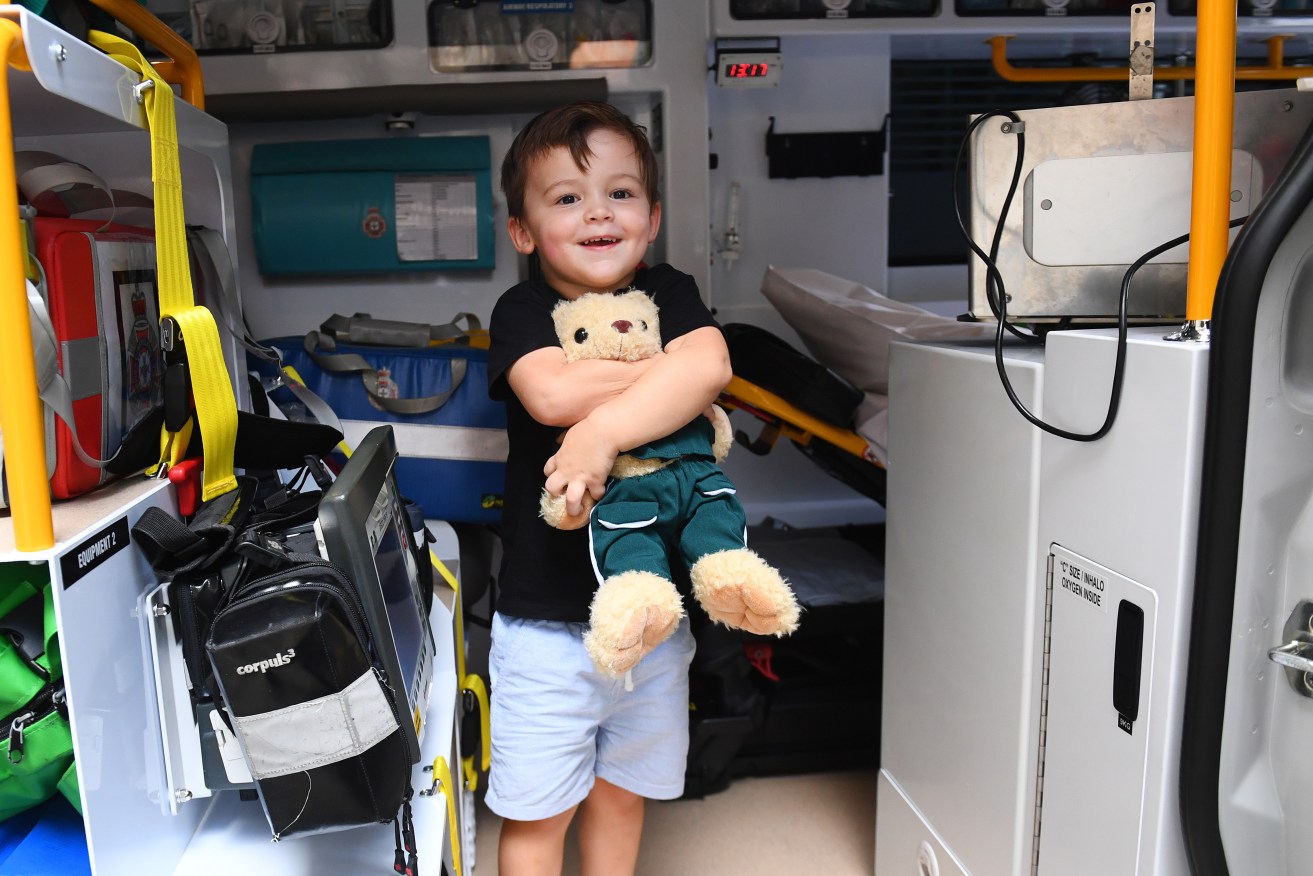 Arthur James 3, poses for a photo in an ambulance outside Parliament House in Brisbane, Wednesday, March 20, 2024. Arthur and his family thanked paramedics that ultimately saved his life from meningococcal meningitis. (AAP Image/Jono Searle) 
