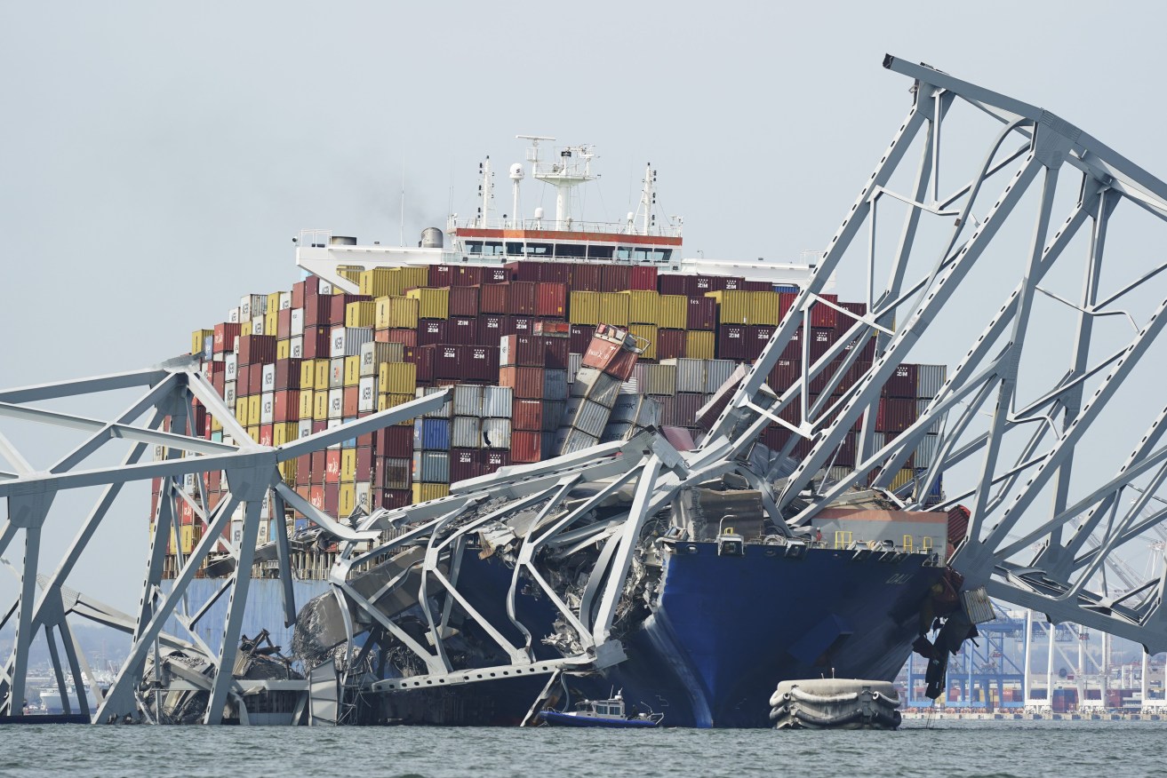 A Coast Guard cutter passes a cargo ship that is stuck under the part of the structure of the Francis Scott Key Bridge after the ship hit the bridge Tuesday, March 26, 2024, in Baltimore, Md. (AP Photo/Steve Helbert