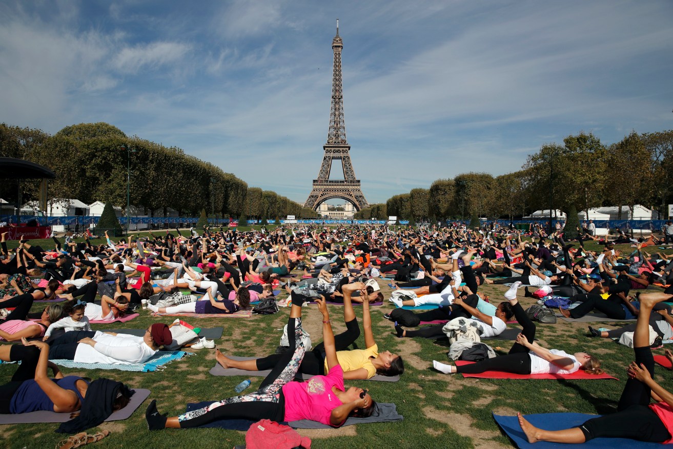 Participants perform yoga in front of the Eiffel Tower as part of the sport event "La Parisienne", in Paris, Saturday, Sept. 8, 2018. (AP Photo/Christophe Ena)