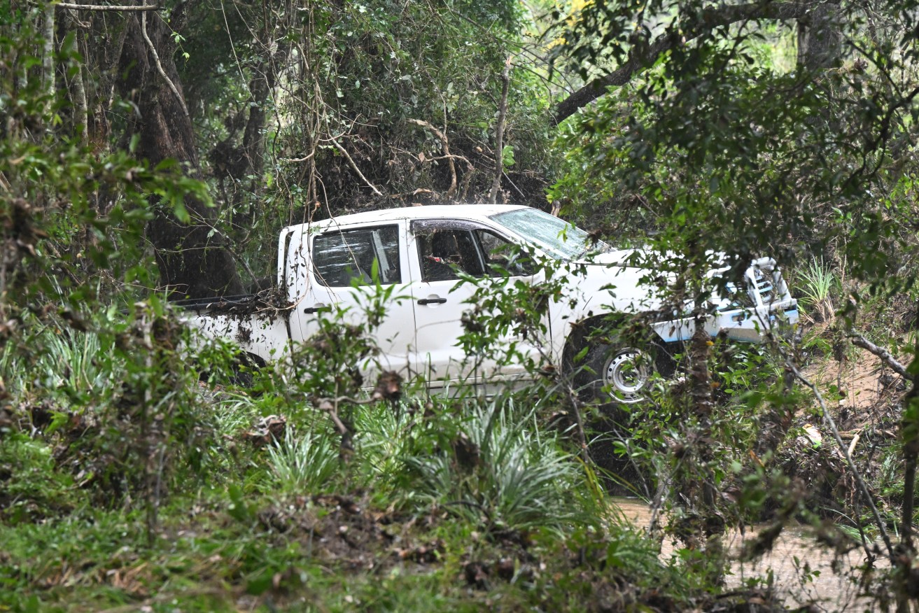 A car is seen after being washed away by floodwaters into a creek where a man has been found dead in Greenbank, south-west of Brisbane, Thursday, April 4, 2024.  A man has died in floodwaters in Queensland's southeast as the state braces for more heavy rain, with NSW also expecting a drenching. (AAP Image/Darren England) NO ARCHIVING