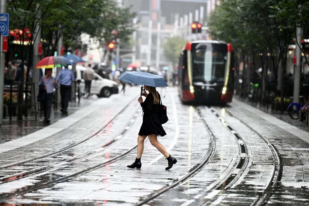People are seen as rain falls in Sydney, Thursday, April 4, 2024. Two troughs are bearing down on eastern Australia bringing heavy rain, thunderstorms and the possibility of flash flooding. (AAP Image/Dan Himbrechts) NO ARCHIVING