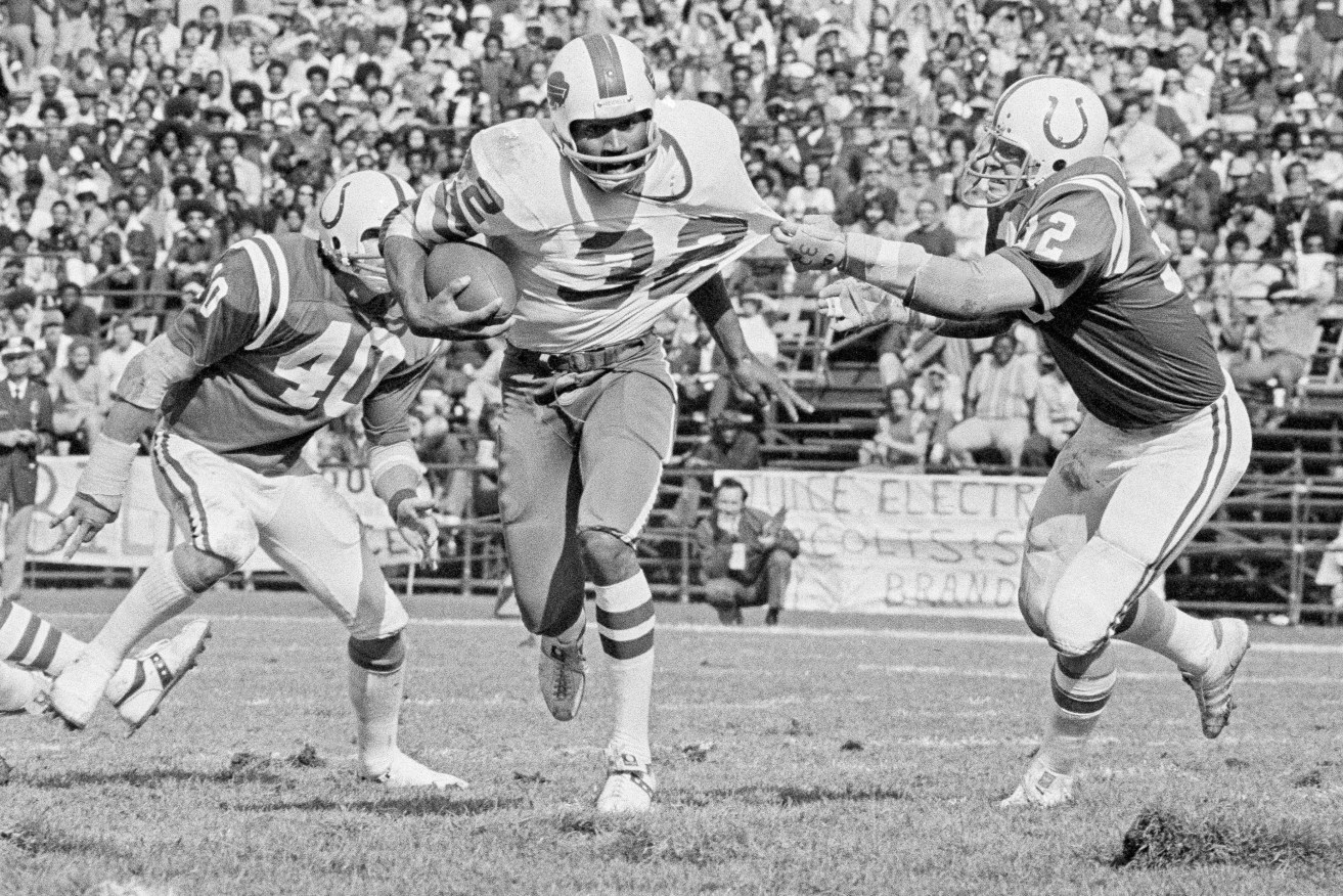 FILE - Buffalo Bulls running back O.J. Simpson (32) has his jersey pulled by Baltimore Colts linebacker Mike Curtis, during the second quarter of an NFL football game in Baltimore, Md., Oct. 12, 1975. Simpson, the decorated football superstar and Hollywood actor who was acquitted of charges he killed his former wife and her friend but later found liable in a separate civil trial, died Wednesday, April 11, 2024, of prostate cancer. He was 76. (AP Photo/File)