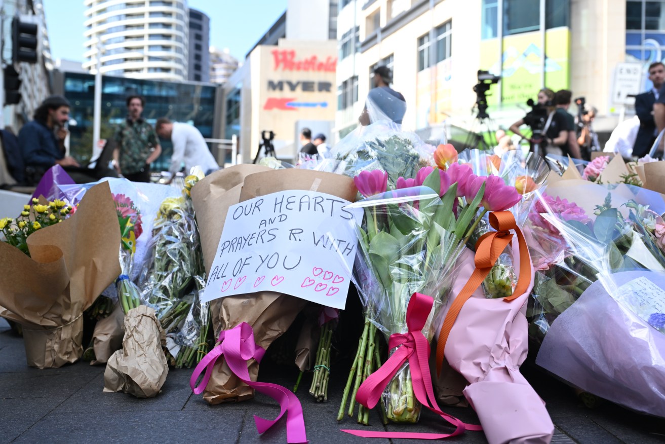 Members of the public pay their respect and lay flowers at the scene of yesterdays mass stabbing at Bondi Junction, Sydney, Sunday, April 14, 2024. The man who fatally stabbed six people in a horror attack at a Sydney shopping centre has been identified as 40-year-old Joel Cauchi who moved to Sydney from Queensland last month. (AAP Image/Dean Lewins) NO ARCHIVING