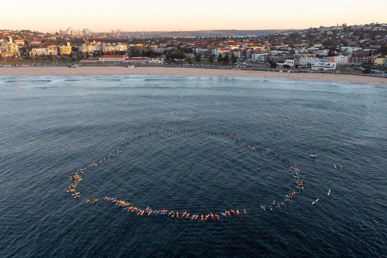 Members of the Bondi Board Riders Club, as well as various local sporting clubs and lifeguards, participate in a Paddle Out on to honour and remember those affected by the recent tragedy at Westfield Bondi Junction, at Bondi Beach in Sydney, Tuesday, April 23, 2024. (AAP Image/Steven Saphore) 