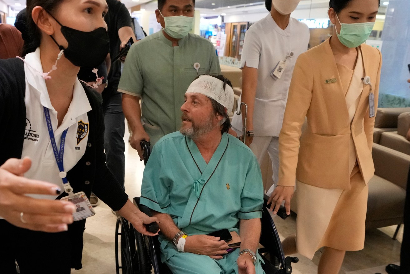 An Australian passenger, center, who was injured on a flight that was battered by severe turbulence, talks to reporters at Samitivej Srinakarin Hospital in Bangkok, Thailand, Thursday, May 23, 2024. The airline's Flight SQ321 was flying from London’s Heathrow airport to Singapore when it hit the turbulence Tuesday, bashing people around inside the plane. (AP Photo/Sakchai Lalit)