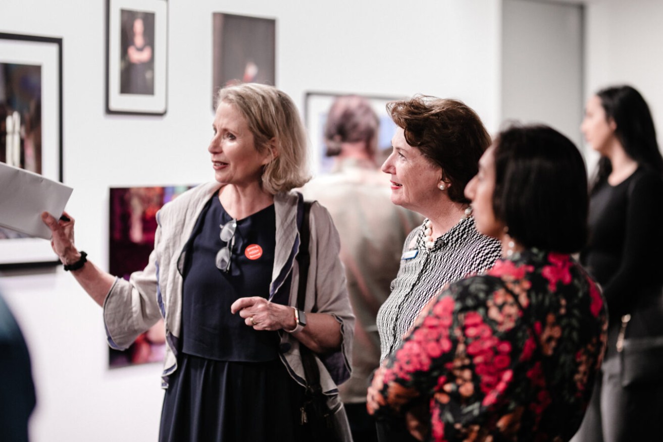 Anna Reynolds shows off last year's Brisbane Portrait Prize to BCC Councillor Vicki Howard.